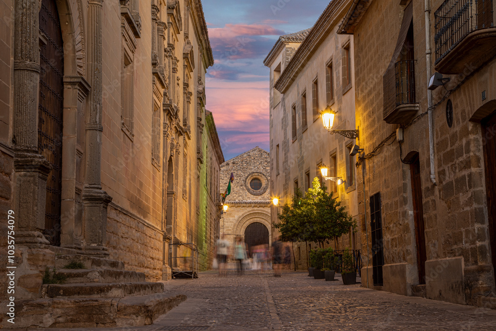 Fototapeta premium Street of the historic center of Baeza with blurred people walking in Baeza, Jaén, Andalusia, Spain at dusk, UNESCO heritage