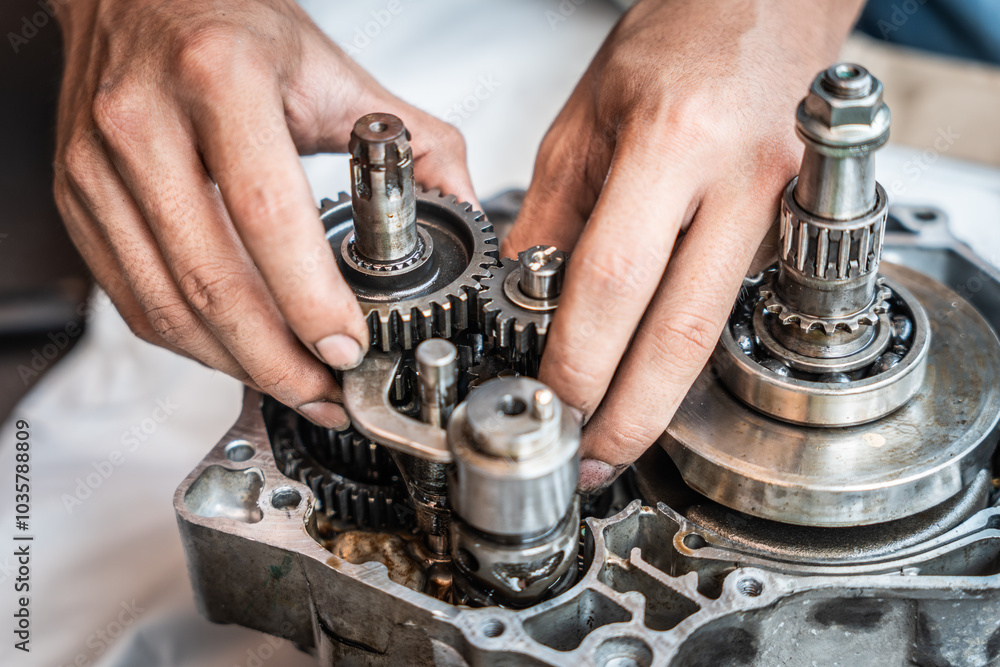 Motorcycle mechanic repairing gearbox ,inspected and looked at all the gear teeth for damage,working at garage, maintenance and repair motorcycle concept