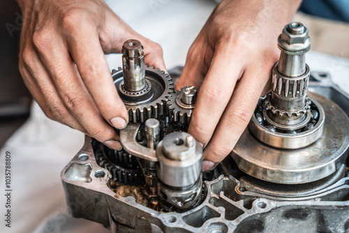 Motorcycle mechanic repairing gearbox ,inspected and looked at all the gear teeth for damage,working at garage, maintenance and repair motorcycle concept photo