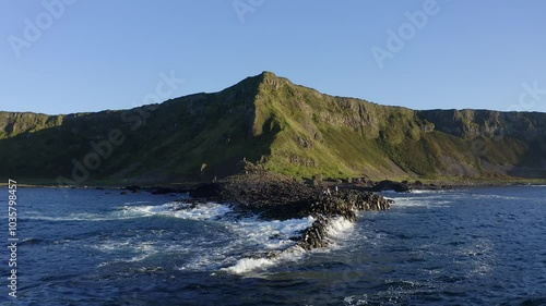 Establishing shot of the Giant's Causeway from the sea, featuring a few tourists on the Grand Causeway.