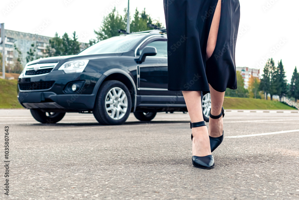 A girl in black walks away from her car. A girl in black walks away from her car.