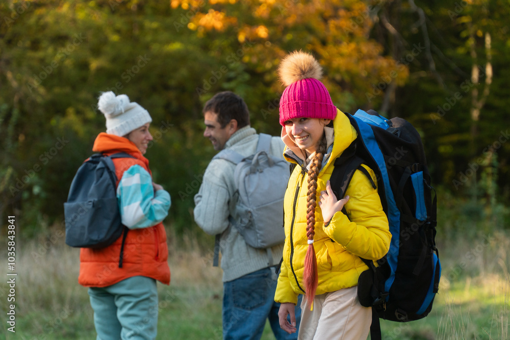 family walking in autumn forest with backpacks, boy in yellow jacket, girl in pink jacket, mother in orange sleeveless jacket, family in hat with pompoms, gen z, father with a big backpack family walking in autumn forest with backpacks, boy in yellow jacket, girl in pink jacket, mother in orange sleeveless jacket, family in hat with pompoms, gen z, father with a big backpack