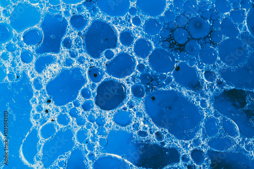 Vibrant blue oil droplets forming abstract patterns in water. photo