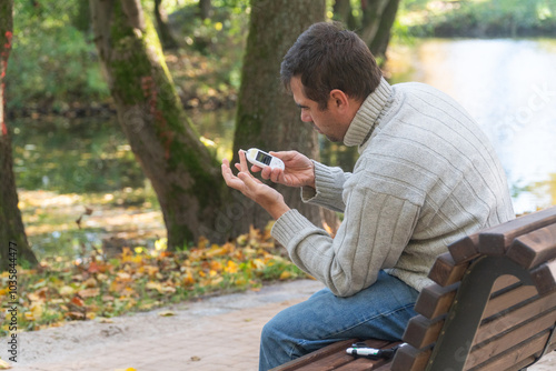 man walks through the forest and sits on a stump, he measures his blood sugar, diabetes, diabetes disease