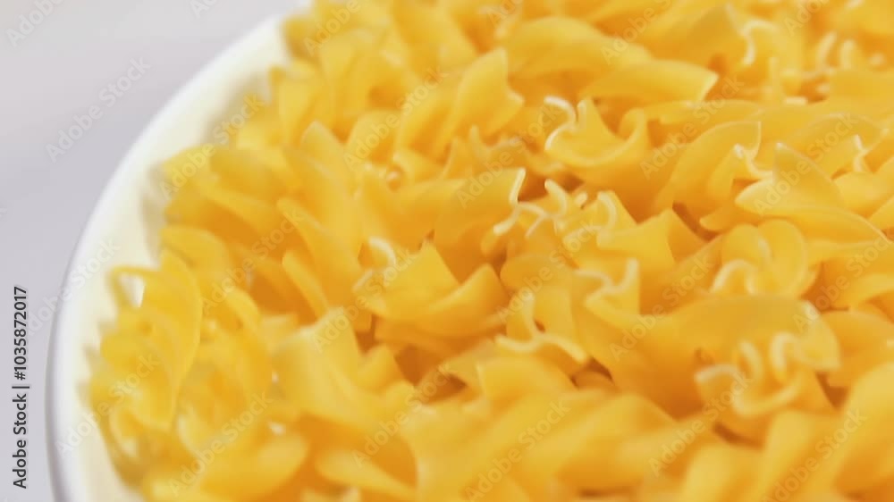 Uncooked Fusilli Pasta on White Plate Rotating against White Background. Fat and Unhealthy Food. Dry Spiral Macaroni. Italian Culture and Cuisine. Raw Golden Pasta Uncooked Fusilli Pasta on White Plate Rotating against White Background. Fat and Unhealthy Food. Dry Spiral Macaroni. Italian Culture and Cuisine. Raw Golden Pasta