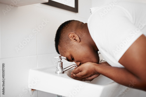 Man, oral hygiene and cleaning mouth by sink in bathroom for morning routine, brushing teeth or fresh breath. Dental care, african person or rinsing in home for personal health, grooming or wellness