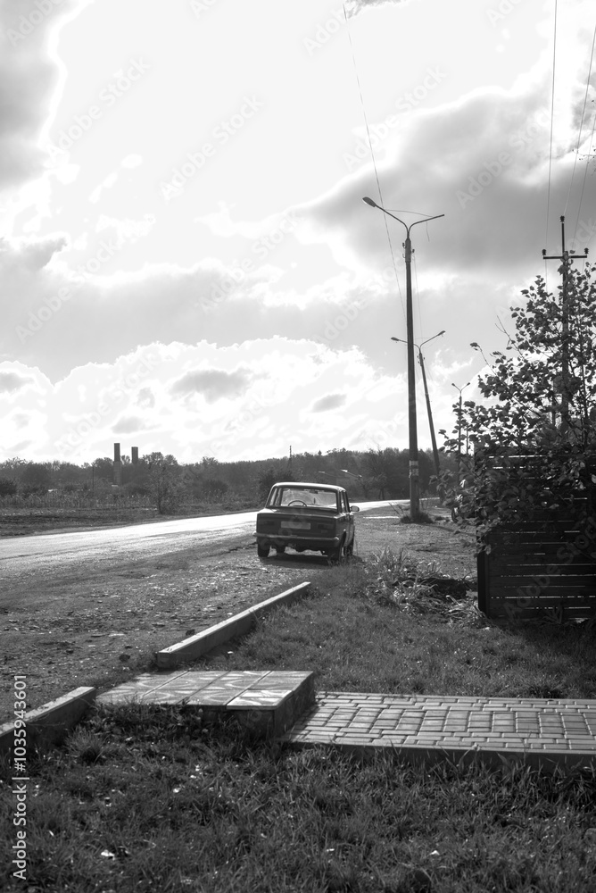 Black and white photo of a car near the road