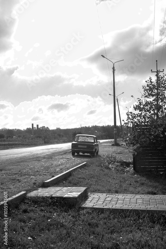 Obraz na płótnie Black and white photo of a car near the road w salonie