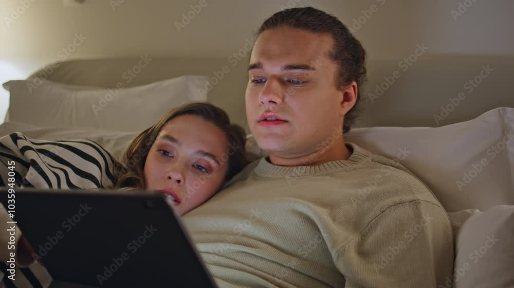 Family watching social media on tablet lying cozy bed closeup. Romantic spouses Family watching social media on tablet lying cozy bed closeup. Romantic spouses