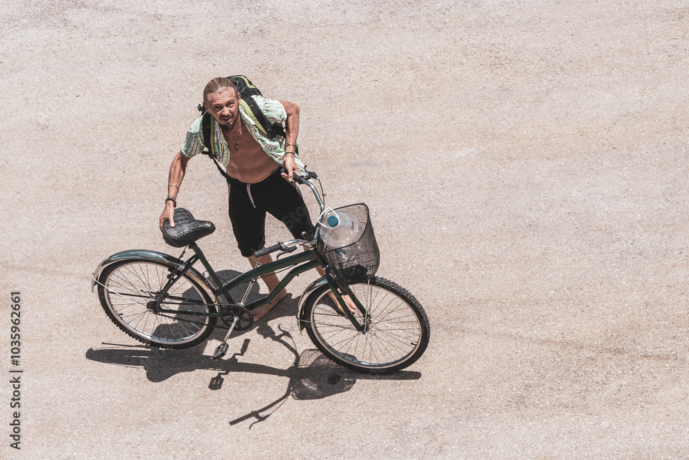 Fototapeta premium Long haired man rides away on a bicycle in Mexico.