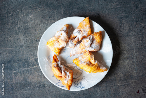 Hungarian crisp sweet pastry ¨csöröge fánk¨ (Angel Wings) with powdered sugar on a plate. 