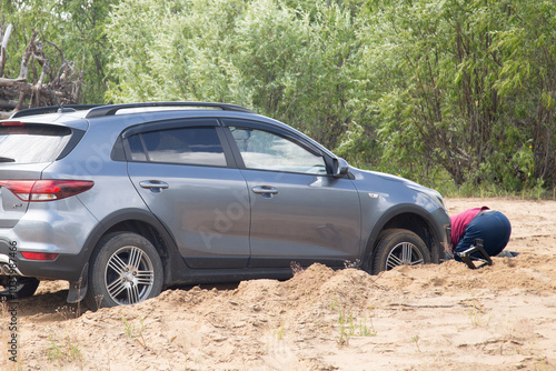 Syktyvkar, Komi Republic, Russia, July 21, 2024, A car truck got stuck on a sandy road.The man is trying to pull out the car. photo