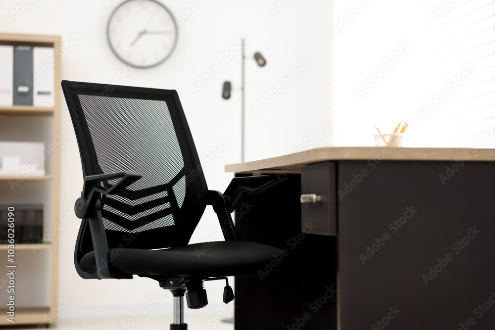 Black chair and wooden desk in office, closeup Black chair and wooden desk in office, closeup