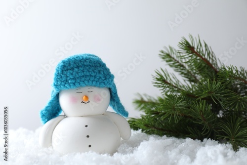 Cute decorative snowman and fir branches on artificial snow against light background