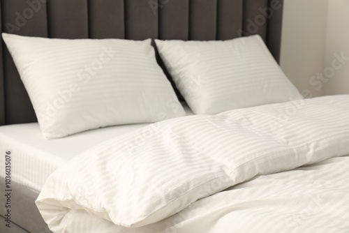 Comfortable bed with clean linens and pillows indoors, closeup photo