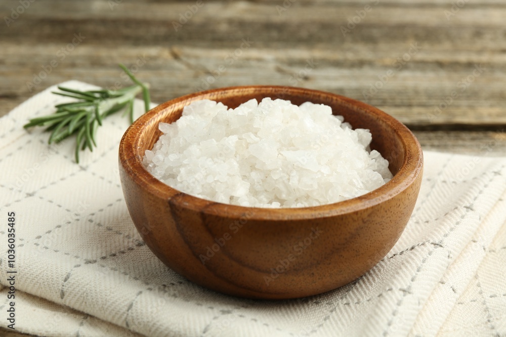 Sea salt in bowl and rosemary on table, closeup Sea salt in bowl and rosemary on table, closeup