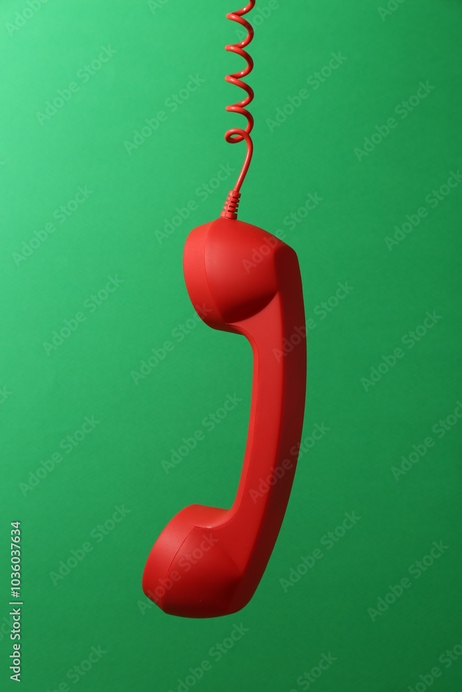 Red corded telephone handset on green background Red corded telephone handset on green background