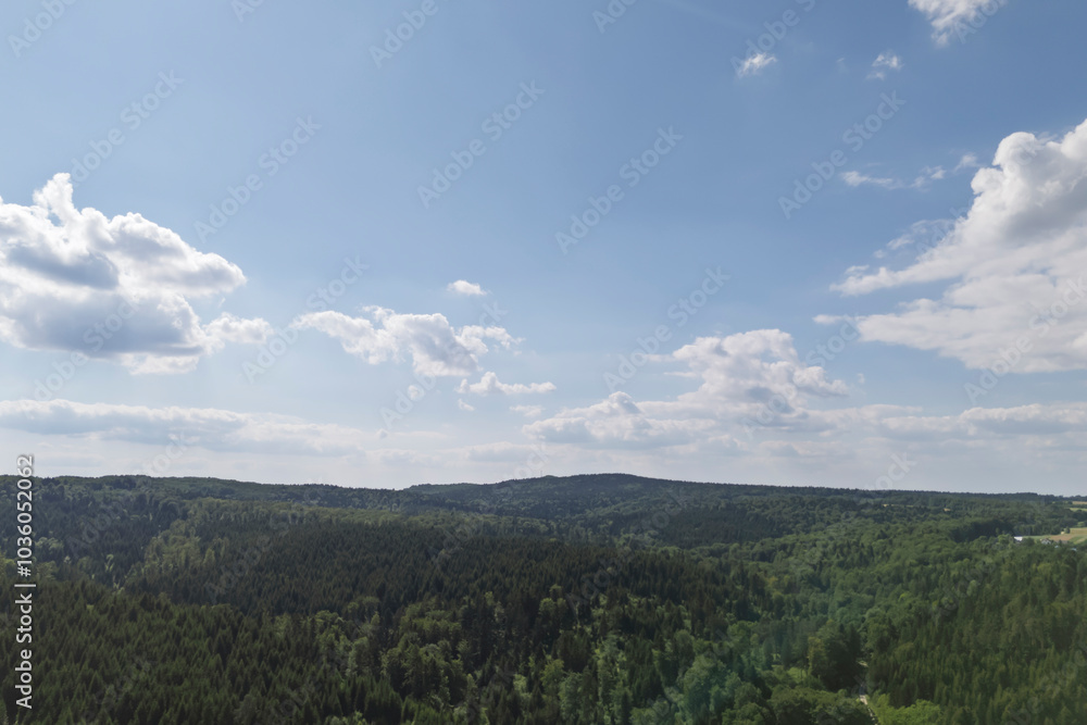 Fototapeta premium Scenic view of lush green hills under a bright blue sky with fluffy clouds. A perfect depiction of nature's beauty and tranquility.