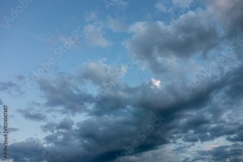 Dramatic evening sky with dark clouds painted against a serene blue backdrop.