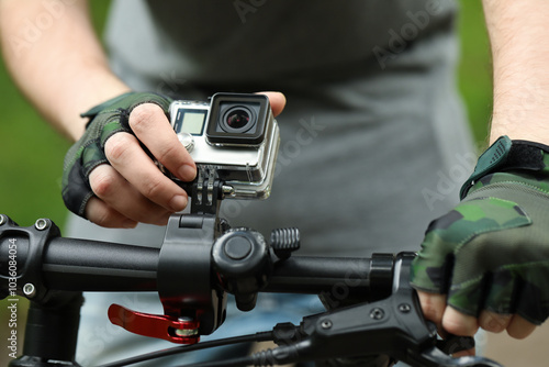 Man riding bicycle with modern action camera outdoors, closeup