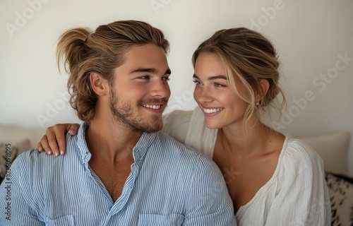 Young couple sharing a joyful moment while relaxing indoors on a cozy sofa in...