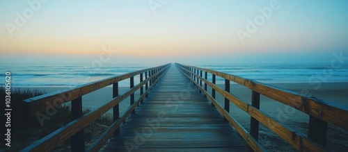 Wooden walkway leading to the ocean at sunrise with a foggy horizon.