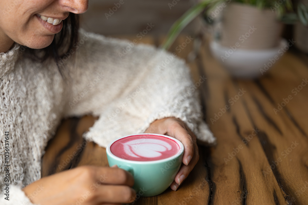Close-up happy young woman smiling in a cafe holding a cup of matcha tea with raspberry, heart-shaped latte art, cappuccino coffee with red foam and heart, decoration with plants, vegan hot drink Close-up happy young woman smiling in a cafe holding a cup of matcha tea with raspberry, heart-shaped latte art, cappuccino coffee with red foam and heart, decoration with plants, vegan hot drink