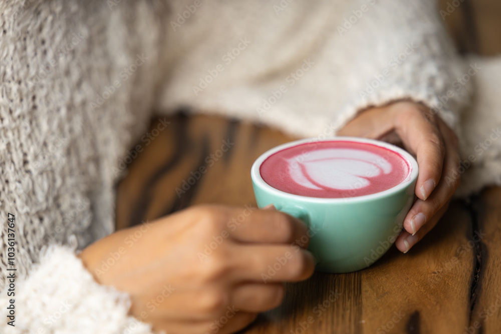 Young woman's hand holds a cup of matcha tea with raspberry or red berries, heart-shaped milk art, cappuccino coffee with red foam and heart, wooden table and decoration with plants, vegan hot drink Young woman's hand holds a cup of matcha tea with raspberry or red berries, heart-shaped milk art, cappuccino coffee with red foam and heart, wooden table and decoration with plants, vegan hot drink