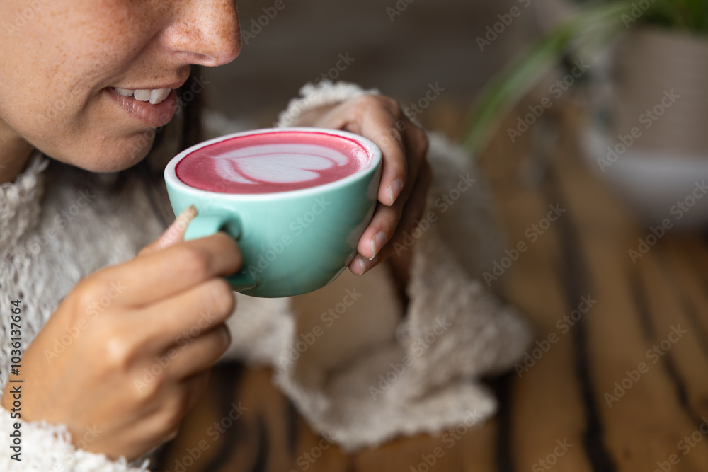 Close-up happy young woman smiling in a cafe holding a cup of matcha tea with raspberry, heart-shaped latte art, cappuccino coffee with red foam and heart, decoration with plants, vegan hot drink Close-up happy young woman smiling in a cafe holding a cup of matcha tea with raspberry, heart-shaped latte art, cappuccino coffee with red foam and heart, decoration with plants, vegan hot drink