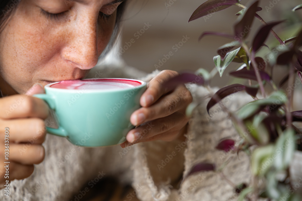 Close-up happy young woman smiling in a cafe holding a cup of matcha tea with raspberry, heart-shaped latte art, cappuccino coffee with red foam and heart, decoration with plants, vegan hot drink Close-up happy young woman smiling in a cafe holding a cup of matcha tea with raspberry, heart-shaped latte art, cappuccino coffee with red foam and heart, decoration with plants, vegan hot drink