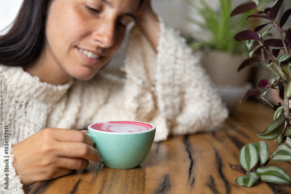 Close-up happy young woman smiling in a cafe holding a cup of matcha tea with raspberry, heart-shaped latte art, cappuccino coffee with red foam and heart, decoration with plants, vegan hot drink Close-up happy young woman smiling in a cafe holding a cup of matcha tea with raspberry, heart-shaped latte art, cappuccino coffee with red foam and heart, decoration with plants, vegan hot drink