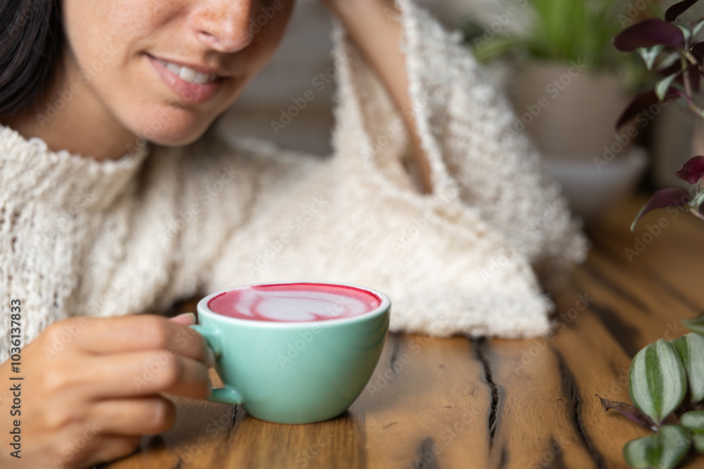 Close-up happy young woman smiling in a cafe holding a cup of matcha tea with raspberry, heart-shaped latte art, cappuccino coffee with red foam and heart, decoration with plants, vegan hot drink Close-up happy young woman smiling in a cafe holding a cup of matcha tea with raspberry, heart-shaped latte art, cappuccino coffee with red foam and heart, decoration with plants, vegan hot drink