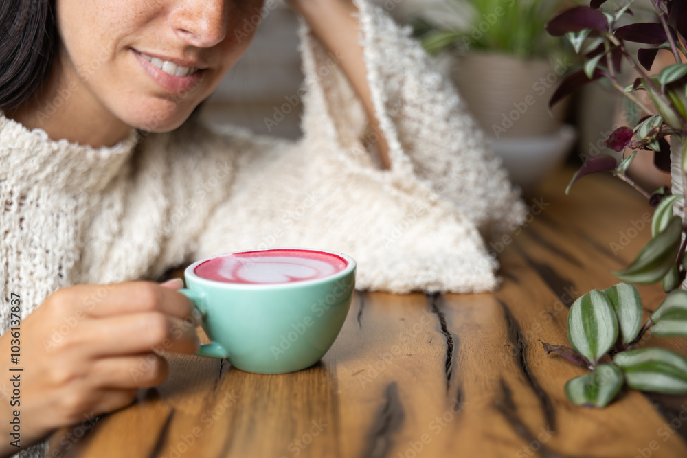 Close-up happy young woman smiling in a cafe holding a cup of matcha tea with raspberry, heart-shaped latte art, cappuccino coffee with red foam and heart, decoration with plants, vegan hot drink Close-up happy young woman smiling in a cafe holding a cup of matcha tea with raspberry, heart-shaped latte art, cappuccino coffee with red foam and heart, decoration with plants, vegan hot drink