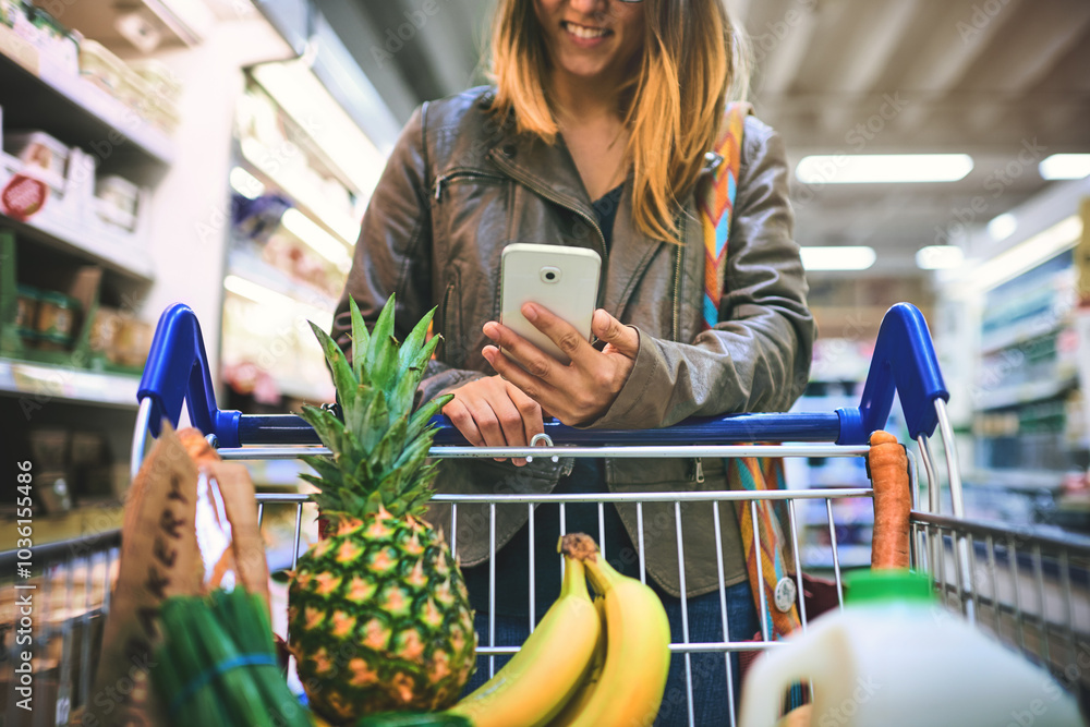 © Koegelenberg Coop/peopleimages.com - Woman, phone and aisle of supermarket for shopping, digital coupon and merchandise deal. Female person, sale and store for options on offer, retail trolley and customer check online app for price © Koegelenberg Coop/peopleimages.com - Woman, phone and aisle of supermarket for shopping, digital coupon and merchandise deal. Female person, sale and store for options on offer, retail trolley and customer check online app for price
