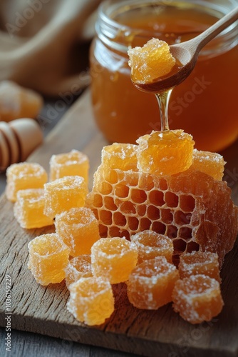 Fresh honey dripping from a wooden dipper into a jar with honeycomb on a wooden surface photo