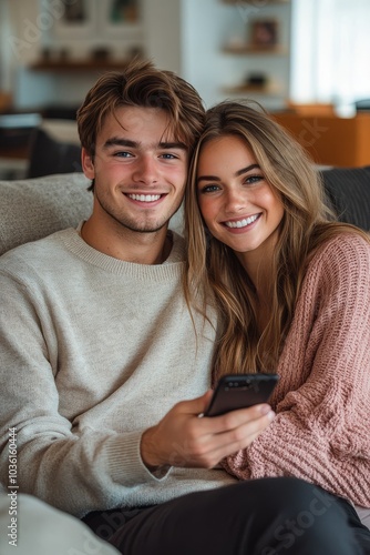 A happy young couple sharing a joyful moment while sitting together in a cozy...