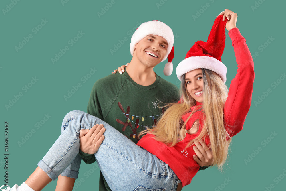 Young couple in Santa hats and Christmas sweaters on green background Young couple in Santa hats and Christmas sweaters on green background