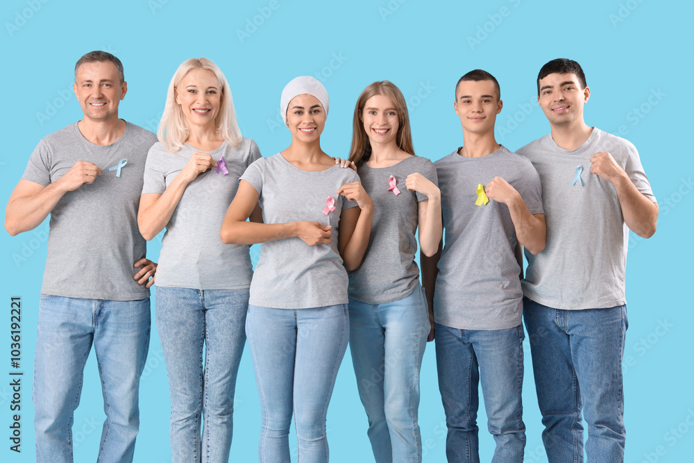 Obraz premium People with different awareness ribbons on blue background. World Cancer Day