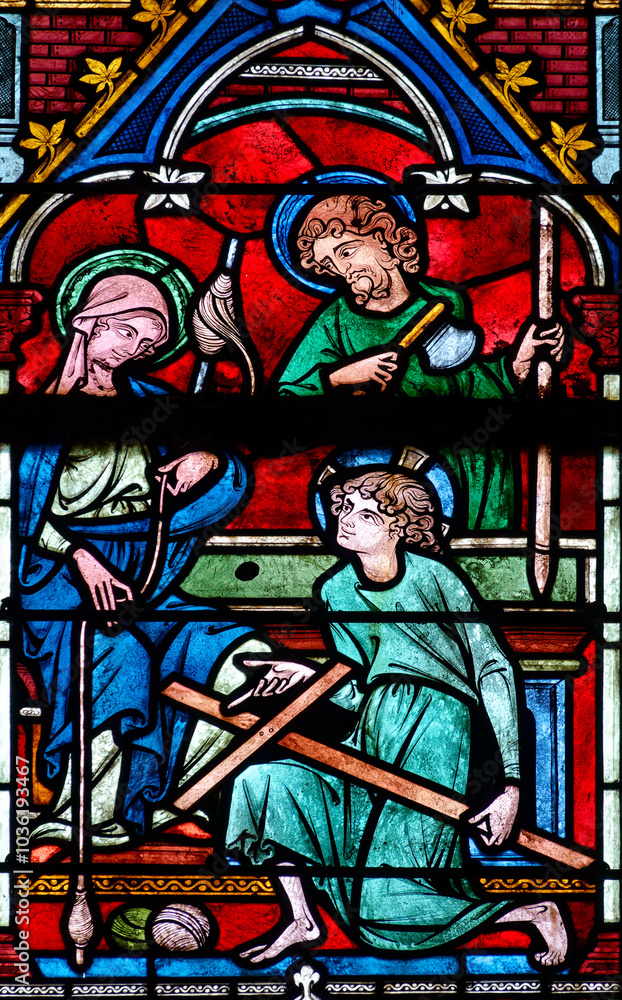 Naklejka premium 2024-10-16, Auxerre, FRANCE. Stained glass (17th century) of Holy family: Jesus infant, Virgin Mary and St Joseph in the workshop of Joseph the carpenter.