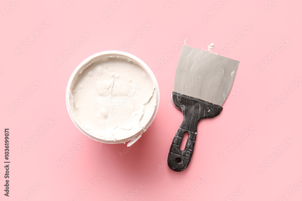 Knife and can of putty on pink background Knife and can of putty on pink background