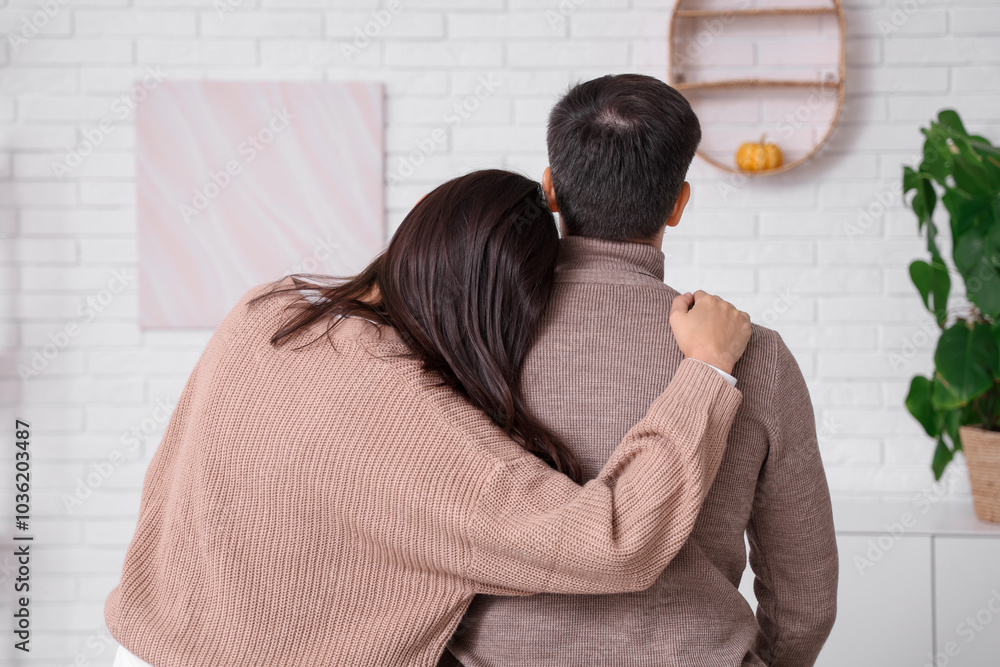 © Pixel-Shot - Young couple hugging at home on autumn day, back view