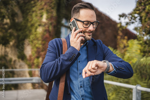 Businessman talk on mobile phone and check time on wrist watch