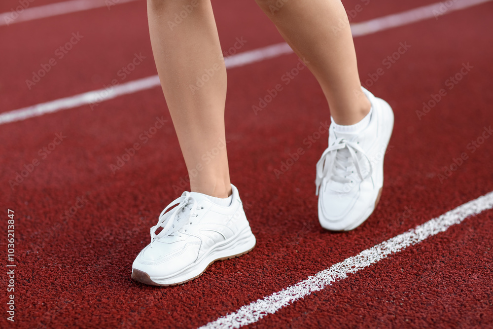 Legs of young woman running at stadium, closeup