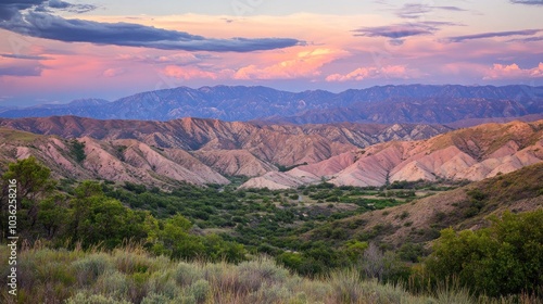 A panoramic view of a valley with rolling hills and a river, bathed in the soft light of a sunset. 