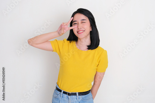 A woman smiling happy and doing two fingers pose on her eye photo