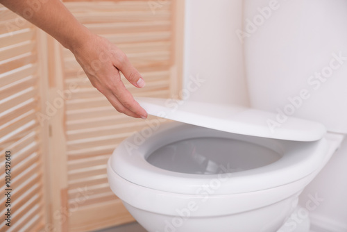 Woman closing toilet seat in bathroom, closeup