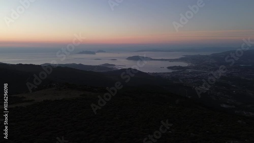 Breathtaking view of Val Miñor at sunset, with the Estelas islands, Vigo's estuary and the Cíes Islands in the distance, taken from Alto da Groba. The camera orbits over the scenic hills. photo