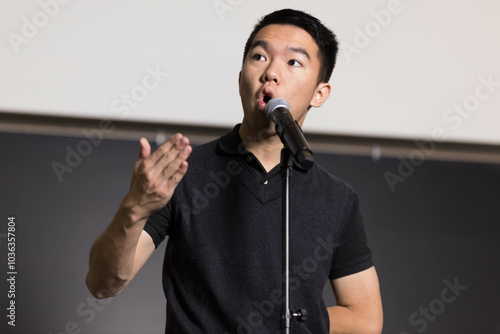 Фотография A young man confidently speaks to an audience in front of a microphone