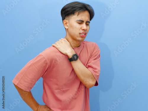 Billede på lærred Portrait of an unhealthy young man holding his waist and back with a sad and painful expression on an isolated blue background
