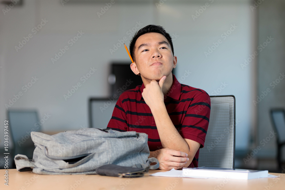 A college student is daydreaming at a library table A college student is daydreaming at a library table